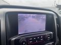 A 2015 GMC Sierra 1500 displaying a rearview camera image on the infotainment screen with parking guidelines and a cloudy outdoor scene visible