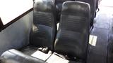 Two black leather bus seats with seatbelts positioned side by side in the interior of a 2014 Freightliner Thomas bus