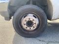 Close-up of the wheel and tire of a 2003 Ford F-450 SD showing visible wear and rust on the rim and tire tread