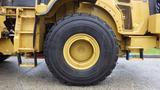 A large yellow tire of a 2019 Caterpillar 972M XE with a rugged tread design and a robust wheel rim