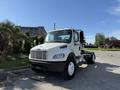 A white 2003 Freightliner M2 106 truck with a black front bumper and cabin seen from the front at an angle without a trailer attached