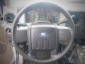 A black steering wheel of a 2008 Ford F-550 with a central Ford logo and various gauges visible in the background