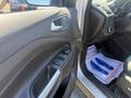 Interior view of a 2014 Ford Escape showing the driver's side door panel with window controls and a glimpse of the driver's seat and floor mat