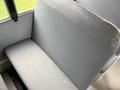 A gray bench seat in a bus with a smooth surface and slightly textured fabric