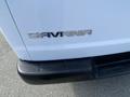 A close-up of the rear of a 2022 GMC Savana displaying the chrome "SAVANA" emblem attached to the white vehicle