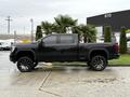 A 2022 GMC Sierra 3500HD in black with oversized wheels parked on a concrete surface featuring a cab and a truck bed design