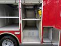 A red 2007 Ford F-550 with open storage compartments featuring metal shelving and a yellow phone mounted on the wall