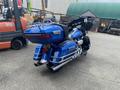 A blue 2017 Harley-Davidson FLHTKL motorcycle with a large backrest and saddlebags features chrome exhaust pipes and detailed front fairings