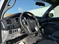 Interior view of a 2015 Toyota Tacoma featuring a black steering wheel and dashboard controls with a gear shift in the center console