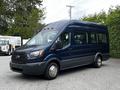 A 2017 Ford Transit 350 in dark blue with large windows and a spacious interior designed for passenger transport