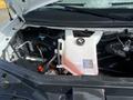 A 2022 GMC Savana engine compartment showing the coolant reservoir with a label and cap, alongside various engine components and wiring