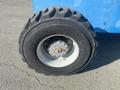 A close-up of a large, rugged tire from a 1997 Genie S-65 4X4 with visible tread patterns and a metallic rim showing signs of wear and rust