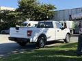 A white 2018 Ford F-150 pickup truck with a short bed and chrome wheels parked at an angle with its tailgate down