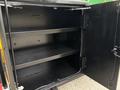 A black metal storage cabinet with two interior shelves and an open door, mounted on the side of a 2015 Freightliner M2 106 truck