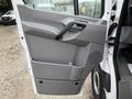 A gray interior door panel of a 2016 Mercedes-Benz Sprinter featuring a handle speaker area and storage compartment