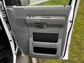 A close-up of the driver's side door panel of a 2011 Ford Econoline featuring gray plastic surfaces and storage compartments