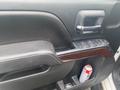 Door panel of a 2015 GMC Sierra 1500 featuring a wooden trim and buttons for power windows and locks