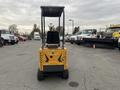 A yellow 2024 AGT Industrial MX12R Mini Excavator with a black seat and protective canopy viewed from the rear in a parking lot