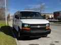 A white 2015 Chevrolet Express van is parked on the side of the road with a black grille and front bumper