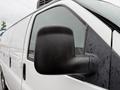 A 2009 Chevrolet Express van with a close-up view of its side mirror covered in rain droplets