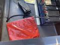 A red tarp folded neatly over a metal surface with visible battery compartments and wires in the background