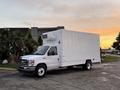 A white 2021 Ford Econoline truck with a large box cargo area and a refrigeration unit on top