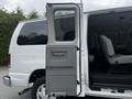 A white 2008 Ford Econoline van with the side door open showing a passenger seat inside