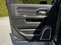 Interior door panel of a 2022 RAM 3500 featuring black leather upholstery and chrome accents with a handle and control buttons