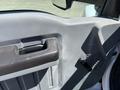 Interior door panel of a 2019 Ford F-750 featuring a textured armrest a handle and a turn knob for window adjustment