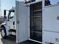 A 2004 Freightliner M2 with an open side compartment revealing a metallic interior and shelves for storage