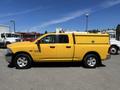 A 2015 RAM 1500 truck painted bright yellow with a utility box in the bed and four doors parked on a lot