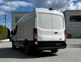 A 2015 Ford Transit van in white with a high roof and rear doors slightly open facing the camera