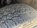 Close-up of a worn tire from a 2016 GMC Sierra 1500 showing deep treads and visible wear patterns on the rubber surface