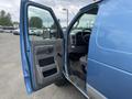 A blue 2010 Ford Econoline van with the driver's side door open revealing the interior including the steering wheel and dashboard