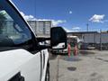 A 2020 Ford F-350 SD pickup truck is parked with its side mirror extended showing a reflection of another vehicle in the background