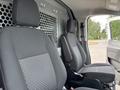 Two front seats of a 2023 Ford Transit van with gray fabric and a partition wall visible behind them