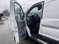 A 2018 Ford Transit van with the driver's door open displaying the interior dashboard and seating area