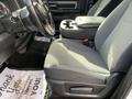 A 2021 RAM 1500 front seat with a grey fabric covering and a console armrest featuring cup holders