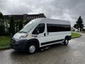 A 2016 RAM Promaster van with a white body and large windows parked on a wet surface