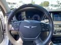 Steering wheel of a 2017 Genesis G80 featuring control buttons and a logo in the center with digital speedometer and tachometer displays behind it
