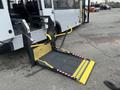 A 2017 Chevrolet Express equipped with a wheelchair lift featuring a yellow platform and safety straps