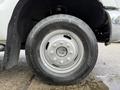 Close-up of a silver wheel with a six-bolt pattern mounted on a 2013 Ford F-350 SD showcasing a black tire with rugged tread and brand markings on the sidewall