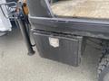 A black storage box attached to the rear of a 2017 Ford F-550 truck with a wooden flatbed