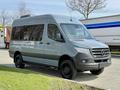 A gray 2019 Mercedes-Benz Sprinter van with black wheels and tinted windows parked on a roadside