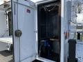A 2018 Ford F-550 with an open side cargo door revealing an empty storage compartment and a coiled blue hose partially visible inside