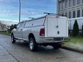 A 2012 RAM 3500 pickup truck with a white cap on the truck bed parked on a street