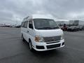 A white 2002 Nissan Van with a high roof and visible front grille parked in an open area with a slight angle towards the viewer