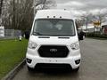 A white 2021 Ford Transit van is parked, showcasing its front view with a black grille and multiple headlights