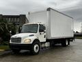 A 2018 Freightliner M2 106 box truck with a white cargo box and side mirrors visible parked on a wet surface