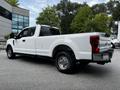 A white 2017 Ford F-250 truck parked with a rear view showing a spacious bed and chrome accents on the back